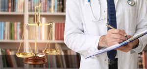 scales of justice placed next to a medical clipboard