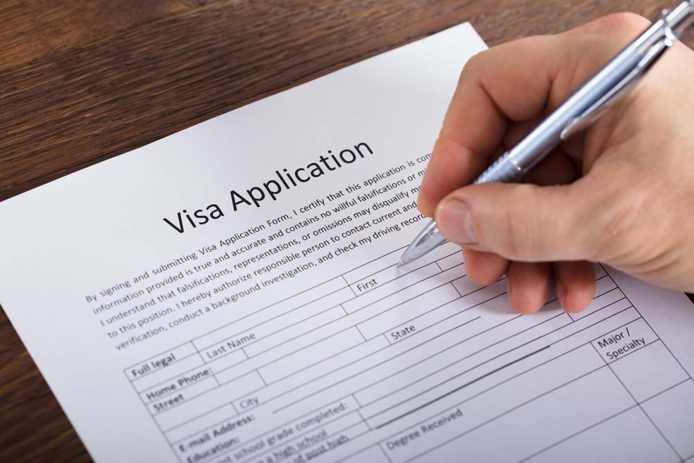 Primer plano de unas manos rellenando un formulario de visa o solicitud.